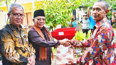 Bupati KLU Nazmul Akhyar didampingi Plt Direktur Bank NTB Syariah menyerahkan bantuan alat pertanian kepada warga. (Iba/ADV)